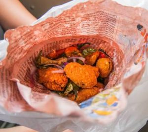Farina hält eine Zeitungstüte mit sri-lankischem Fingerfood fest.